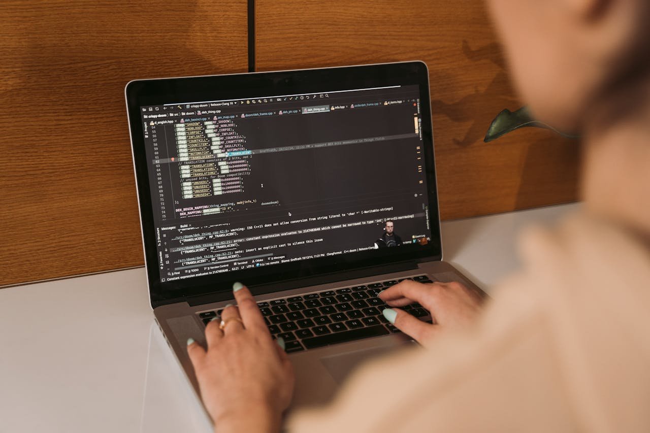 Close-up of a woman coding using a laptop in an office environment, showcasing modern technology.